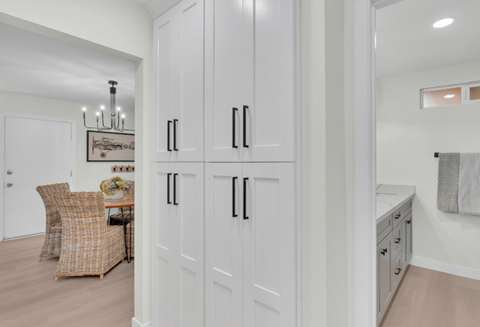 a large white kitchen with white shaker cabinets and a dining room with a table